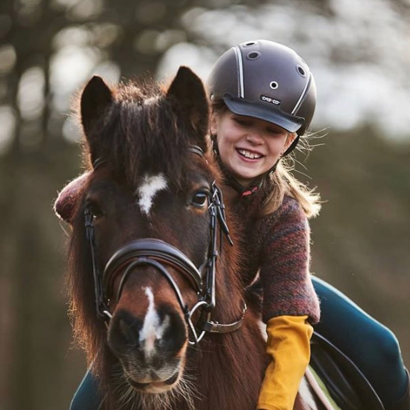 Kind mit Casco-Reithelm auf einem Pony