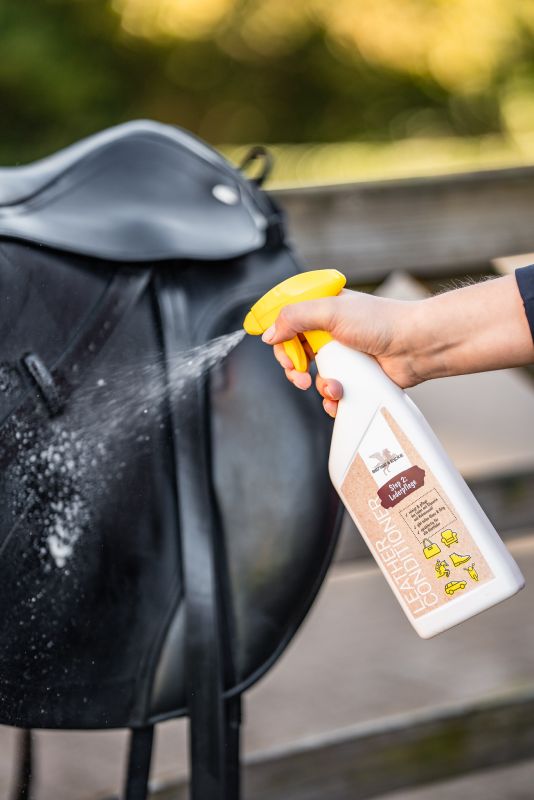 Lederpflege-Spray wird auf einen schwarzen Sattel aufgetragen